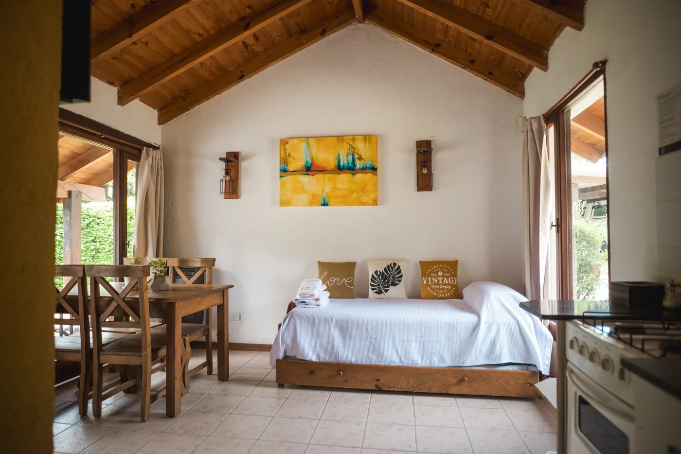 Interior de la Cabaña Chica de Los Álamos: estar-cocina de madera con comedor, sofá y cocina