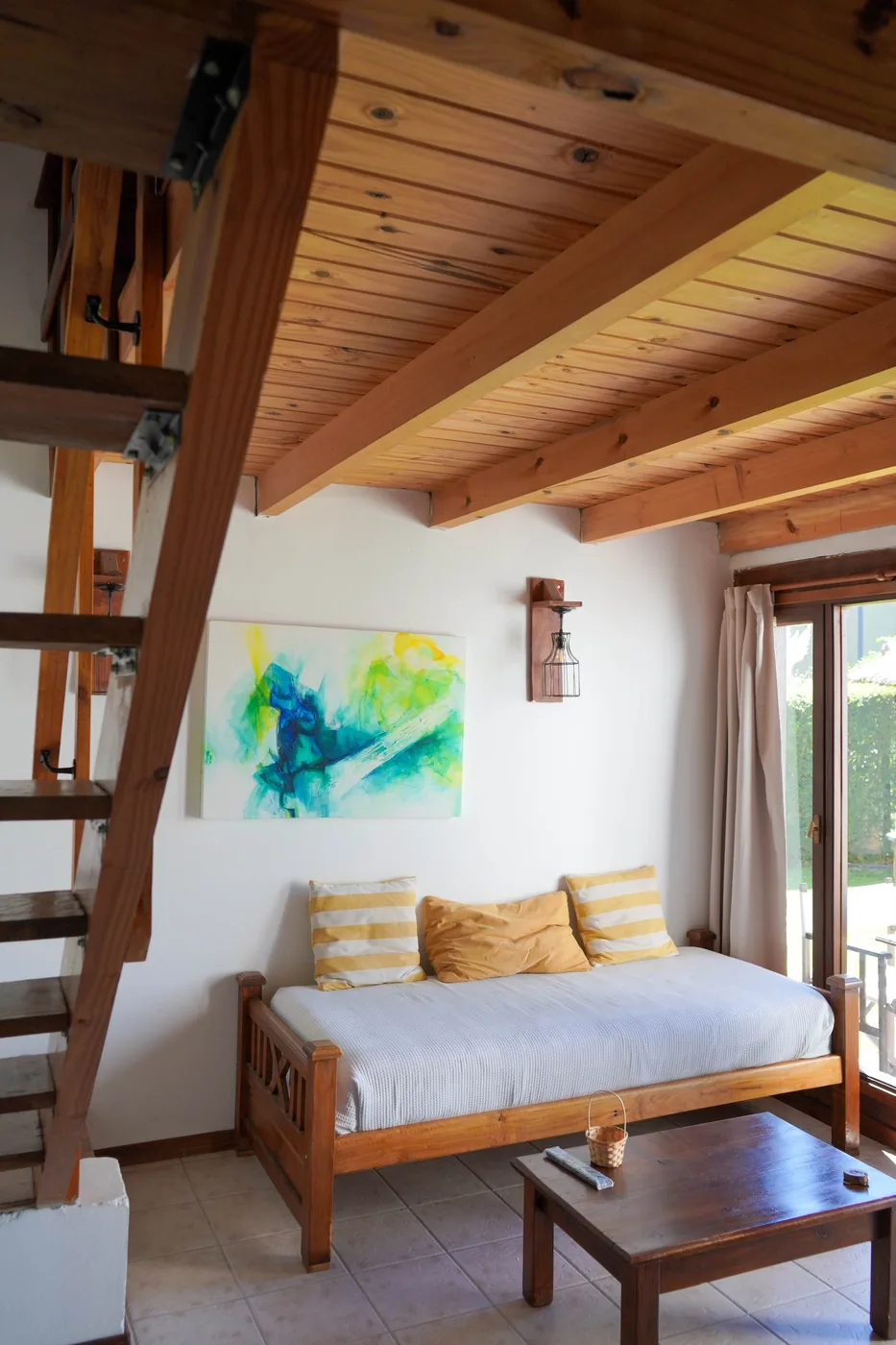 Interior de la Cabaña Grande de Los Álamos: living con escalera al entrepiso y techo de madera