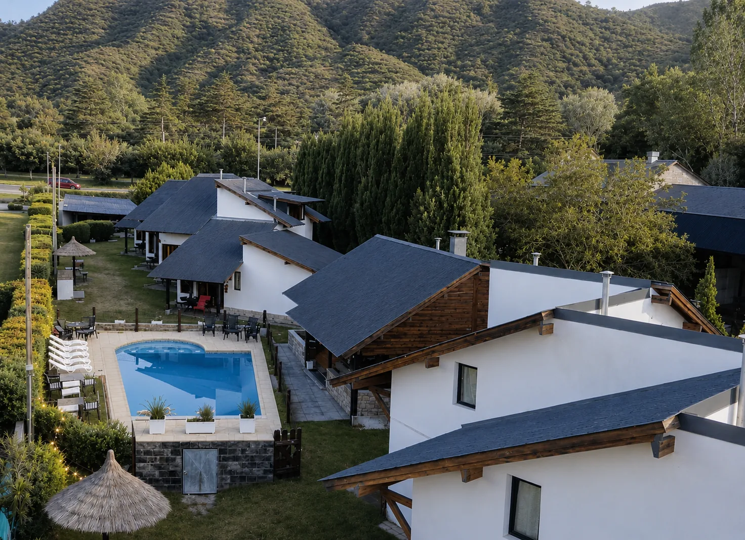Vista aérea del complejo Los Álamos en Villa General Belgrano, con la pileta, las cabañas y las sierras de fondo